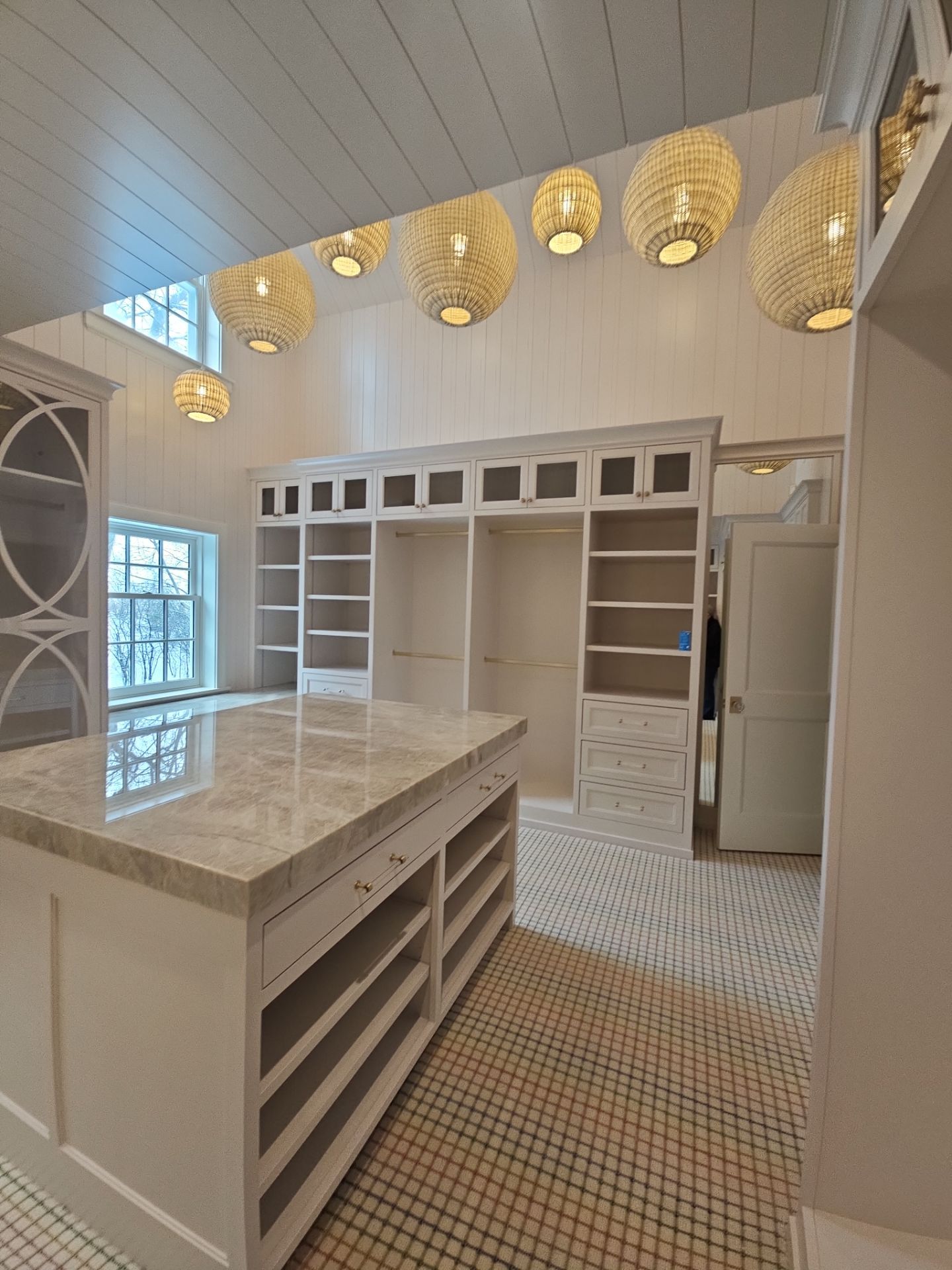Custom closet with soft pink cabinetry and woven pendant lighting